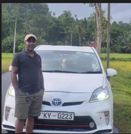 Mahesh Jeewantha standing with his white Toyota Prius in Ahangama
